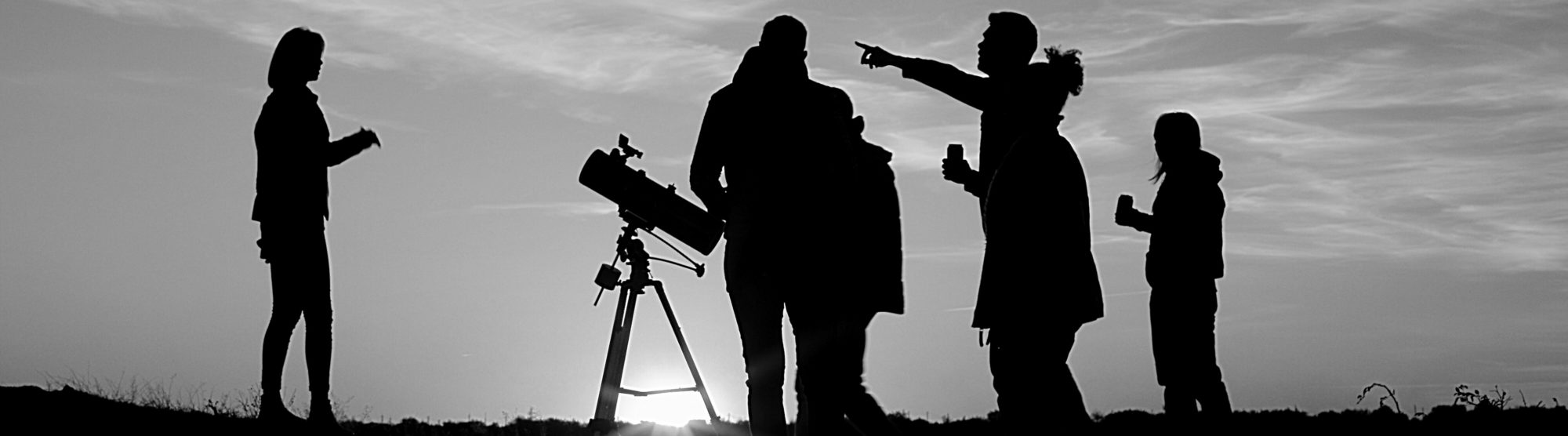image shows a group of people gathered together with a medium-sized telescope at sunset, used as a metaphor for network discovery